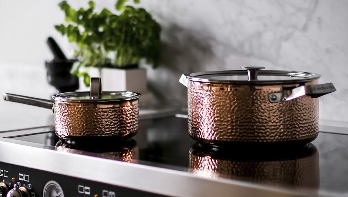 Två kopparfärgade kastruller från Vargen & Thor på induktionshäll – exklusiv design med hamrad finish för ett stilrent och funktionellt kök.