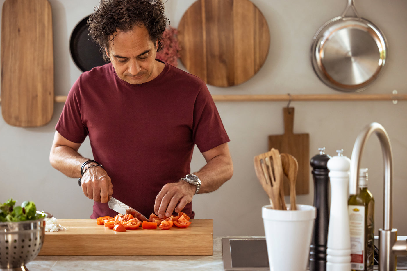 Markus Aujalay i sitt kök, skär tomater med ett av sina egna köksredskap – professionell precision och kvalitet för hemmakocken.