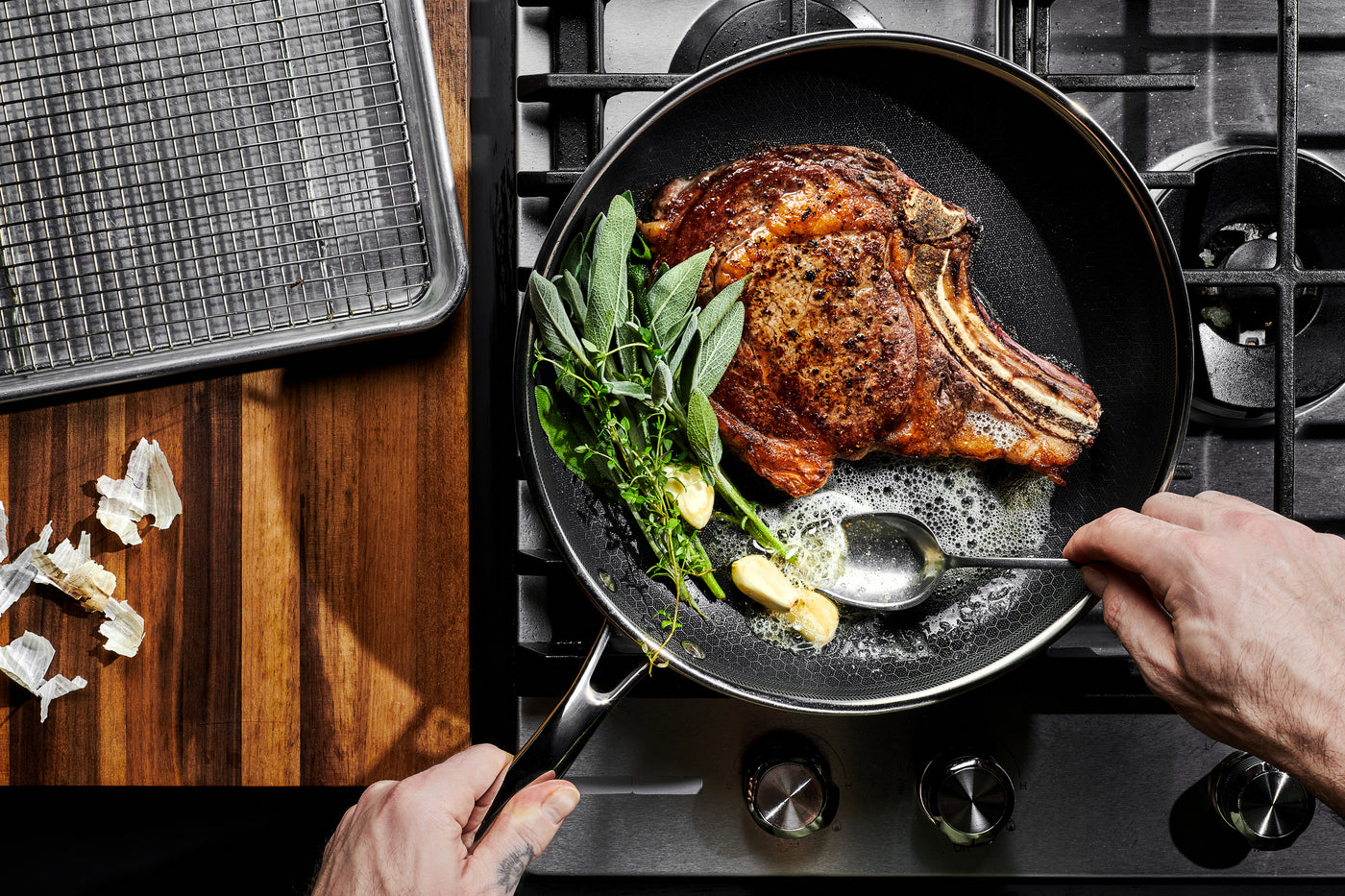 HexClad stekpanna med entrecôte, vitlök och örter i stekpanna på gasspis – premium hybridstekpanna för induktion och proffsmatlagning.