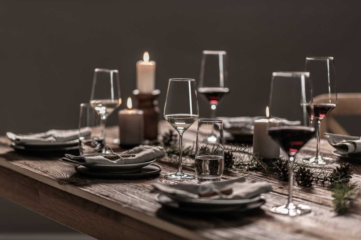 Dukat matbord med stilrena glas från Zwiesel Glas, tända ljus och tallrikar, redo för en inbjudande middag i varm belysning.
